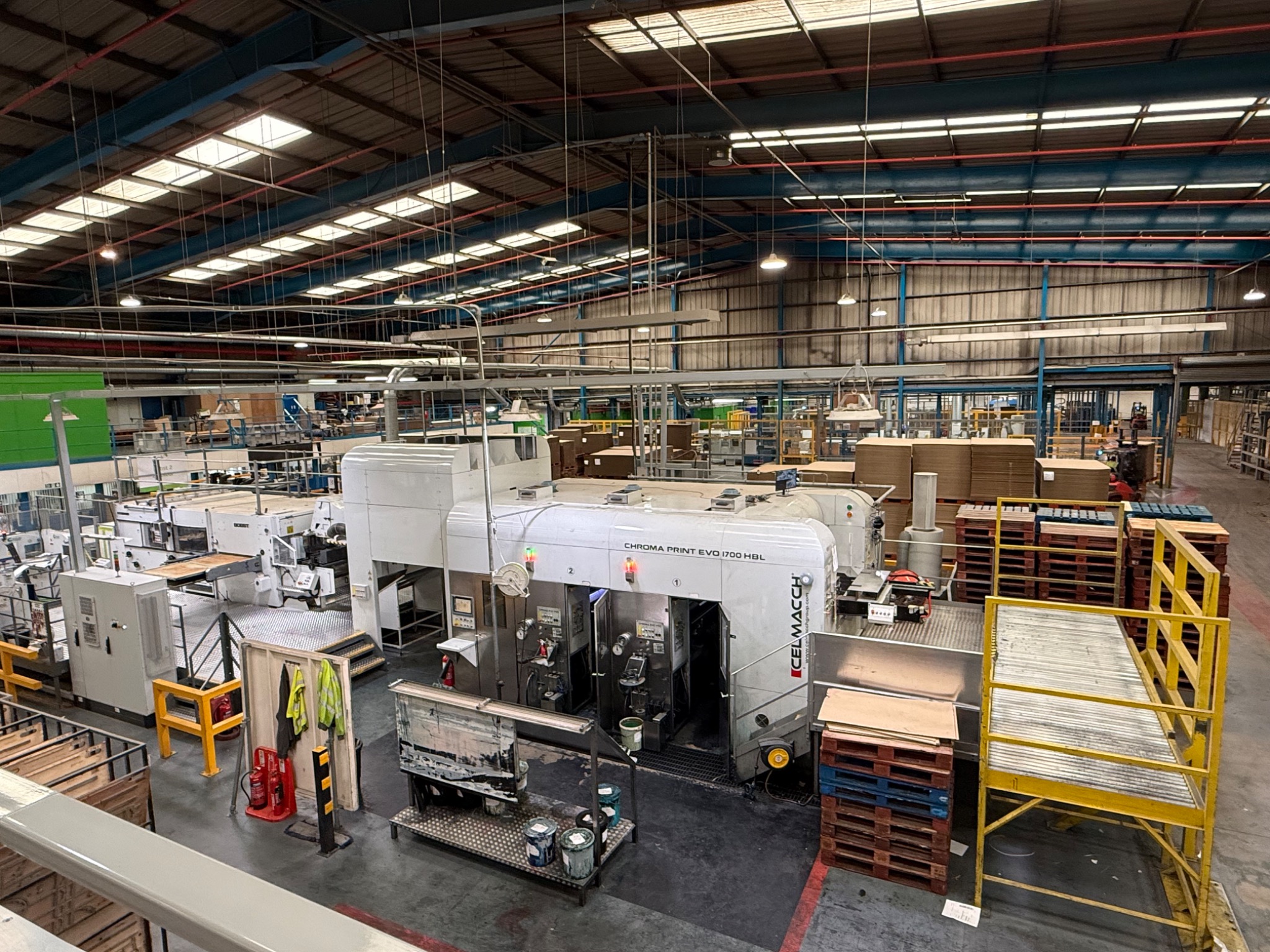 Wide view of corrugated printing and converting machinery on an active factory floor